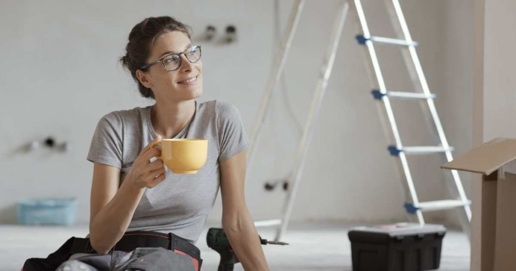 woman on the floor with a mug, in front of a ladder and toolbox